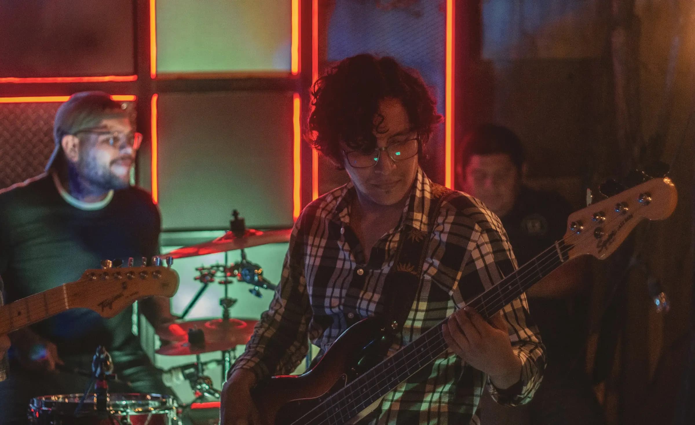 A band playing under red and green stage light in a small club